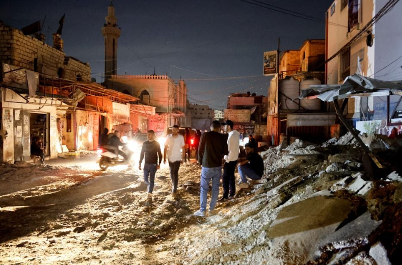 Warga Palestina berdiri di jalan setelah serangan Israel, di kamp pengungsi Jenin di Tepi Barat yang diduduki Israel, 9 November 2023. REUTERS/Raneen Sawafta Memperoleh Hak Lisensi
